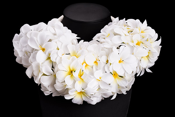 A White Braided Leather Band Necklace Decorated With Rings Of White Plastic Flowers