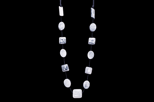 A Long Leather Band Necklace With Thirteen Different Shaped Grey And Black Patterned Resin Beads