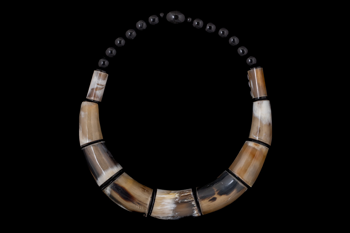 A Necklace Of Nine Buffalo Horn Curved And Graduated Tubular Beads And Black Round Resin Beads