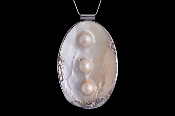 A Mother-Of-Pearl Shell Large Oval Pendant, Inlaid With Three White Blister Pearls And Bordered With A Silver Plated Patterned Frame.
