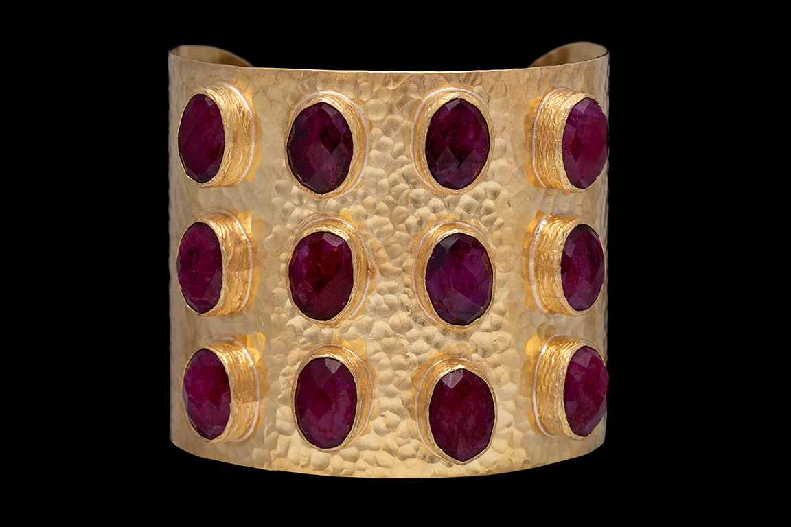 A Gold Plated Hammered Surface Open Cuff With Twelve Ruby Facetted Ovals In Gold Plated Frames