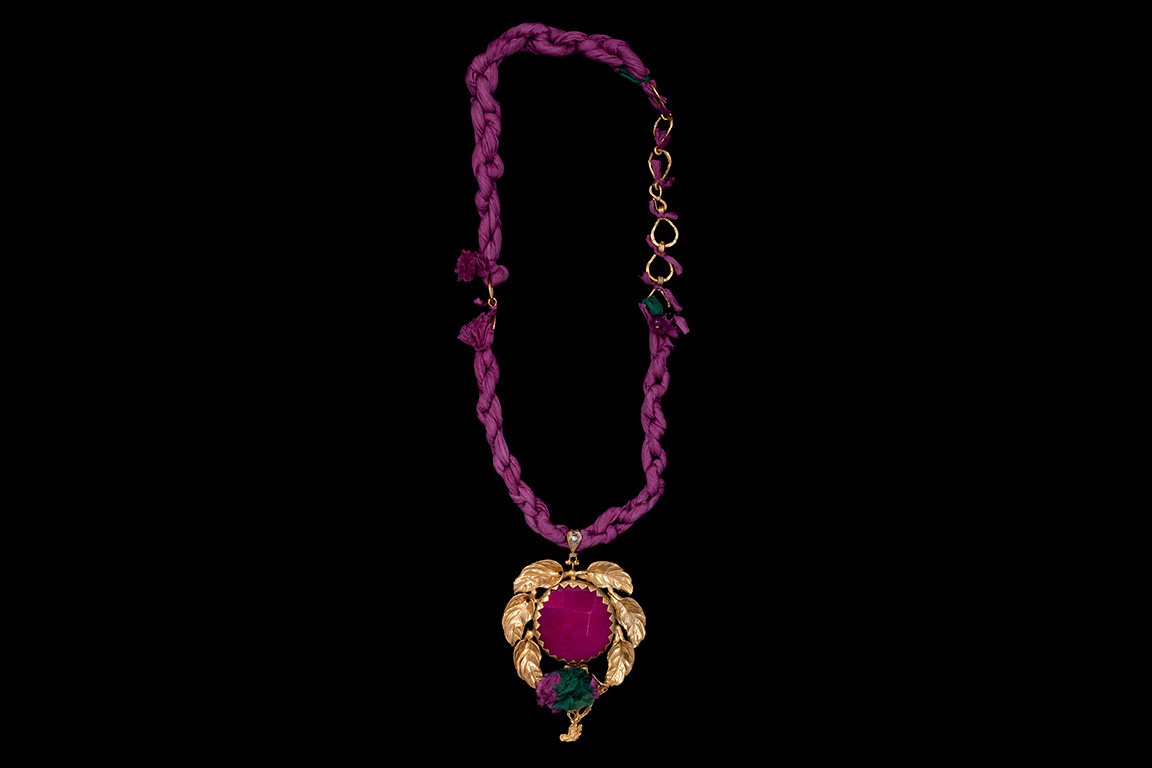 A Gold Plated Leaf Patterned Pendant With A Fuchsia Dyed Agate Circular Centre On A Silk Necklace