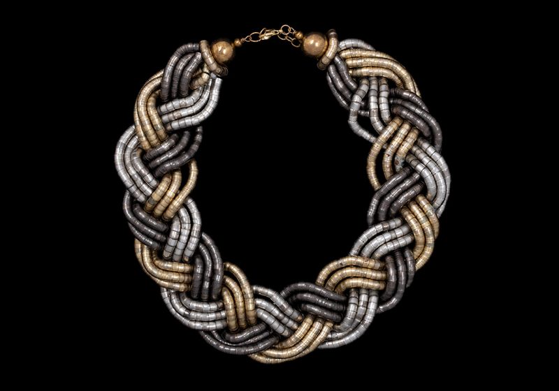 A Braided Necklace With Three Golden Metal, Three Silvered Metal, And Three Gunmetal Flexible Bands