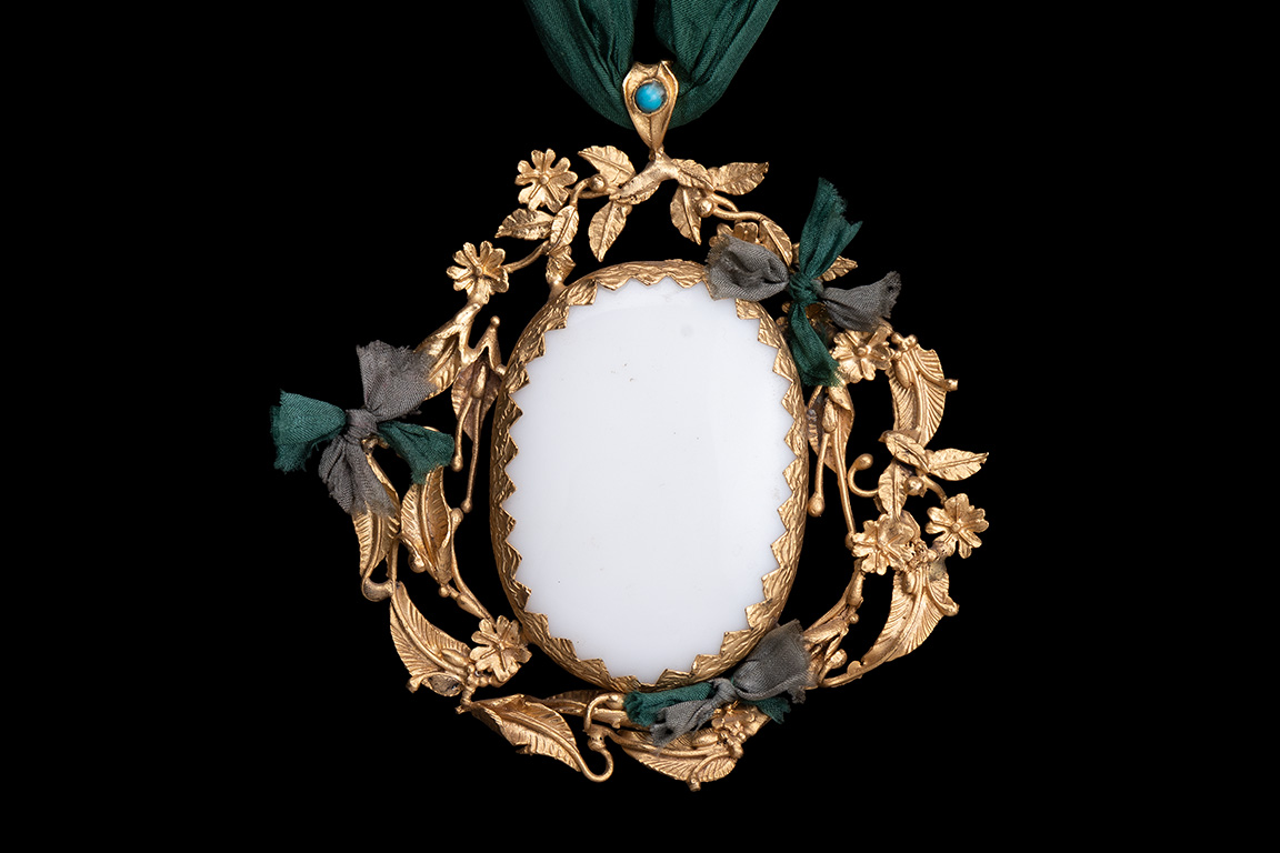 A Gold Plated Floral Patterned Oval Pendant With A White Agate Centre On A Green Silk Long Necklace