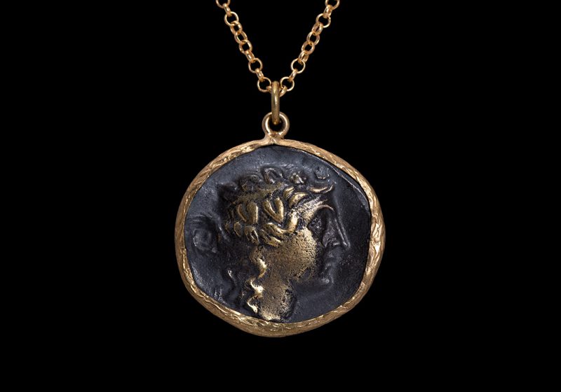 A Gold Plated Circular Pendant With A Copy Of An Ancient Roman Coin On A Long Chain Necklace