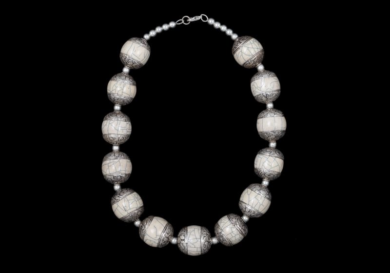 An Afghan Necklace Of Cream Coloured Crackled Horn Oval Beads With Patterned Silver Ends