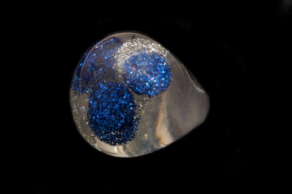 Clear Resin Large Domed Ring Containing Clusters Of Metallic Blue And Silver Glitter Dust