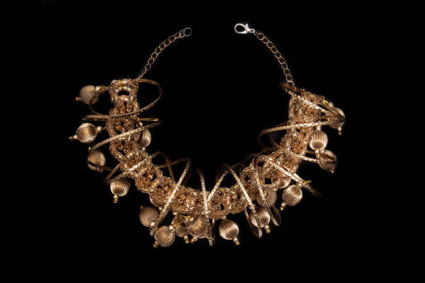 A Necklace Of Golden Metal Interlocking Filigree Bands And A Coiled Band Decorated With Fluted Beads