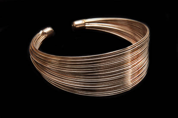 A Tapered Open Cuff Of Thirty Rose Golden Metal Curved Bands