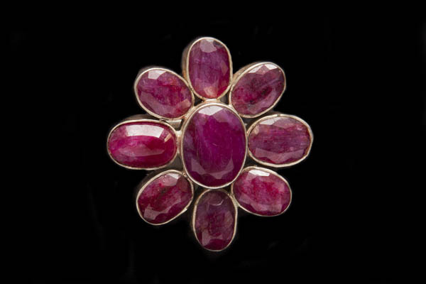 A Large Silver Floral Patterned Circular Ring Inlaid With Nine Ruby Oval Facetted Cabochons