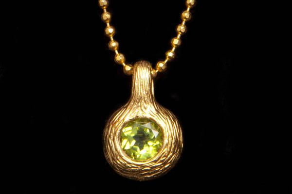 A Gold Plated Circular Pendant Inlaid With A Peridot Facetted Cabochon On A Gold Plated Necklace