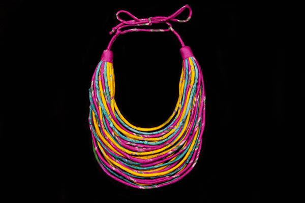 A Long Necklace Of Thirty Graduated Patterned Bands Of Multicoloured Re-Cycled Sari Silk