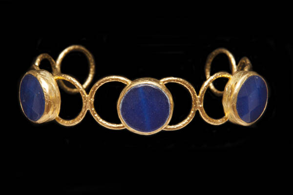 A Golden Metal Ten Rings Open Cuff Decorated With Three Dark Blue Dyed Agate Circular Facetted Cabochons