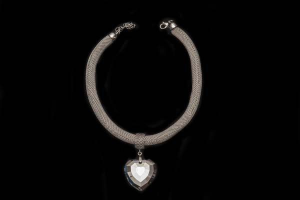 A Silvered Wire Mesh Tubular Necklace With A Clear Facetted Mirrored Glass Heart Shaped Pendant