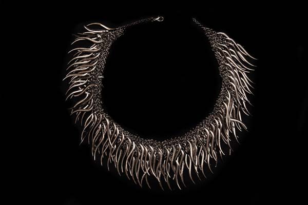 A Dark Silvered Metal Wide Mesh Banded Necklace With A Fringe Of Dark Metal Curved Narrow Drops