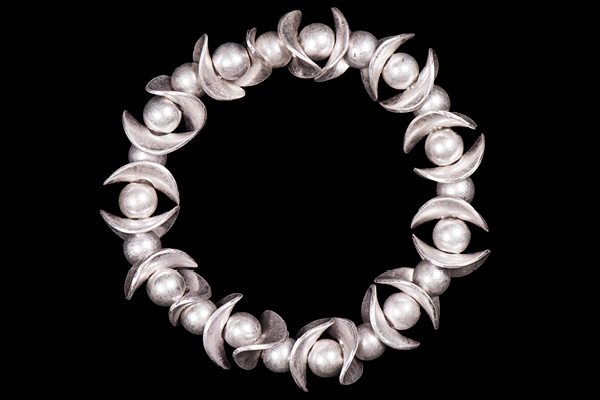 An Elasticated Bracelet Of Silvered Metal Round Beads And Thin Curved Oval Shaped Beads