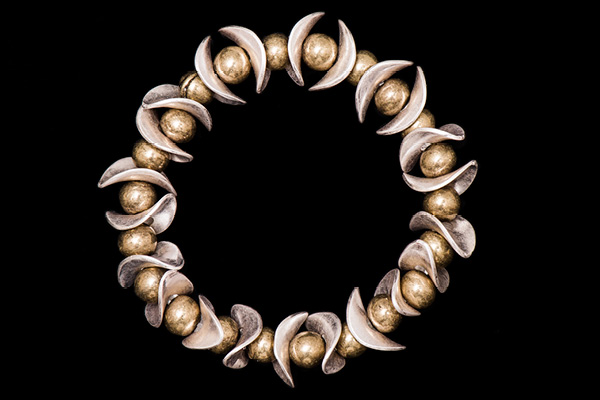 An Elasticated Bracelet Of Golden Metal Round Beads And Silvered Metal Thin Curved Oval Shaped Beads