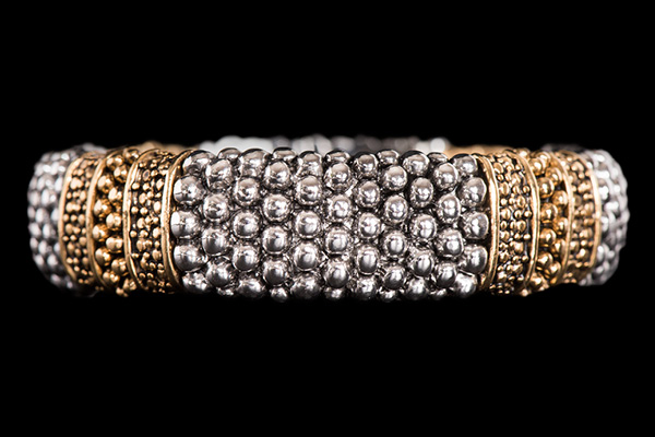An Elasticated Bracelet Of Silvered Metal And Golden Metal Panels Each Decorated With Round Beads
