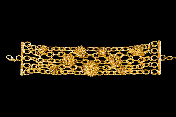 A Golden Metal Five Strand Chain Links Bracelet Decorated With Nine Round Hollow Patterned Beads