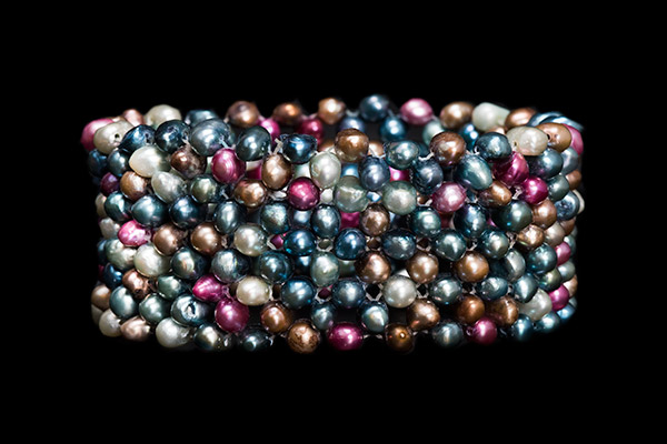 An Elasticated Bracelet Of White, Blue, Silver, Pink, Grey, And Gold Dyed Small Freshwater Pearls
