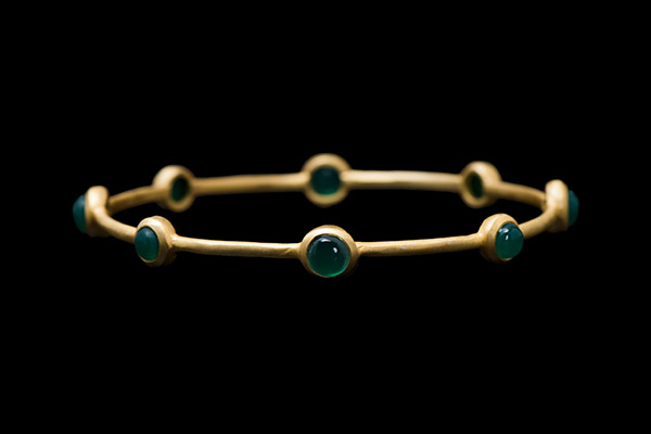 A Matt Gold Plated Bangle Decorated With Eight Emerald Domed Circular Cabochons