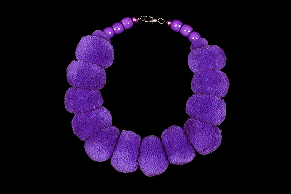 A Necklace Of Twelve Large Purple Wool Pompoms And Six Purple Facetted Resin Barrel Beads