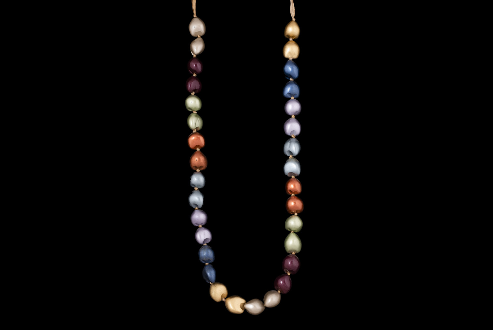 A Long Knotted Golden Silk Band Necklace With Thirty-Two Kukui Nuts, Dyed With Eight Different Colours