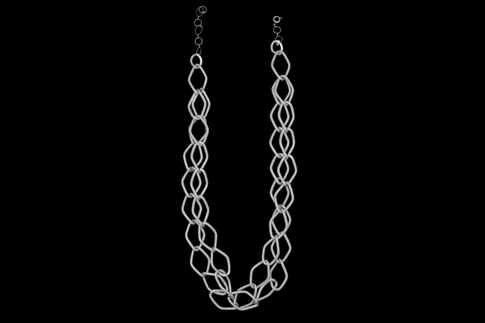 A Silvered Metal Long Two Strand Necklace Of Interlocking Diamond Shaped Patterned Loops.