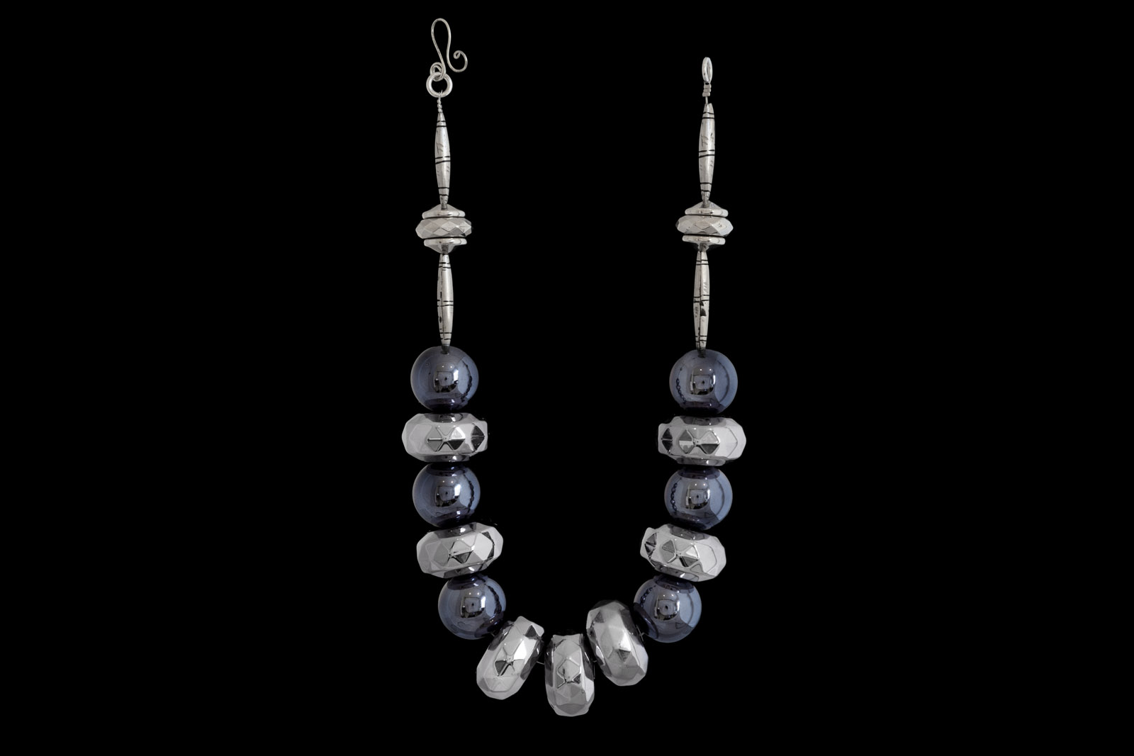 A Necklace Of Six Gunmetal Large Round Hollow Beads, And Seven Large Dark Silvered Metal Facetted Rondellese