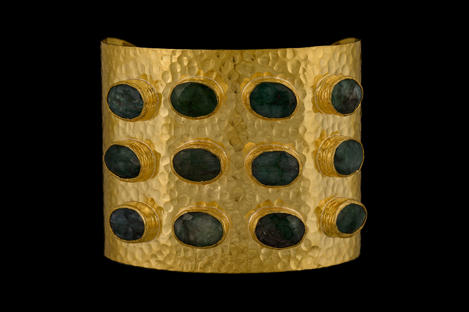 A Gold Plated, Hammered Surface, Open Cuff, With Twelve Gold Plated Oval Frames, Each Inlaid With An Emerald Facetted Cabochon.