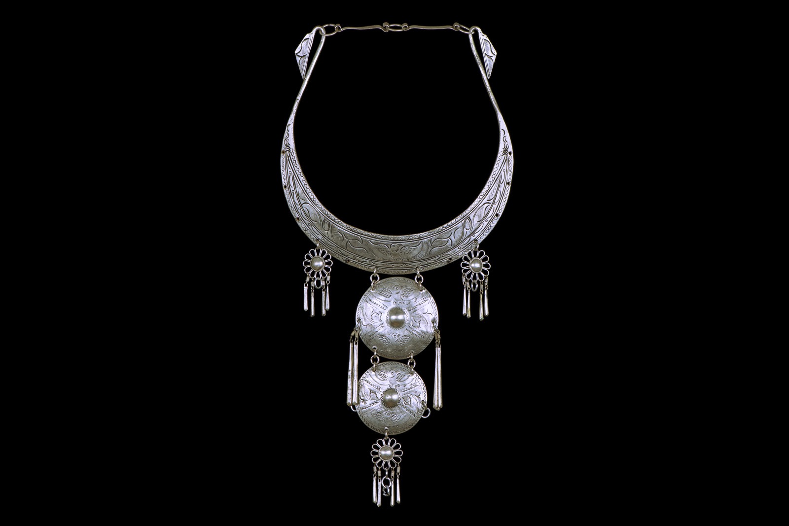 A Miao Silvered Metal Curved Patterned Band Necklace With A Two Linked Patterned Discs Pendant And Three Small Floral Patterned Pendants. China.