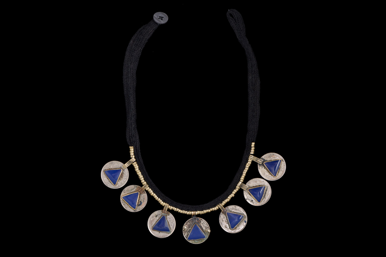 A Kuchi Necklace With A Black Braided Wool Band And Six Silvered Metal Coin Pendants, Each With A Triangular Panel With A Blue Glass Inlay.