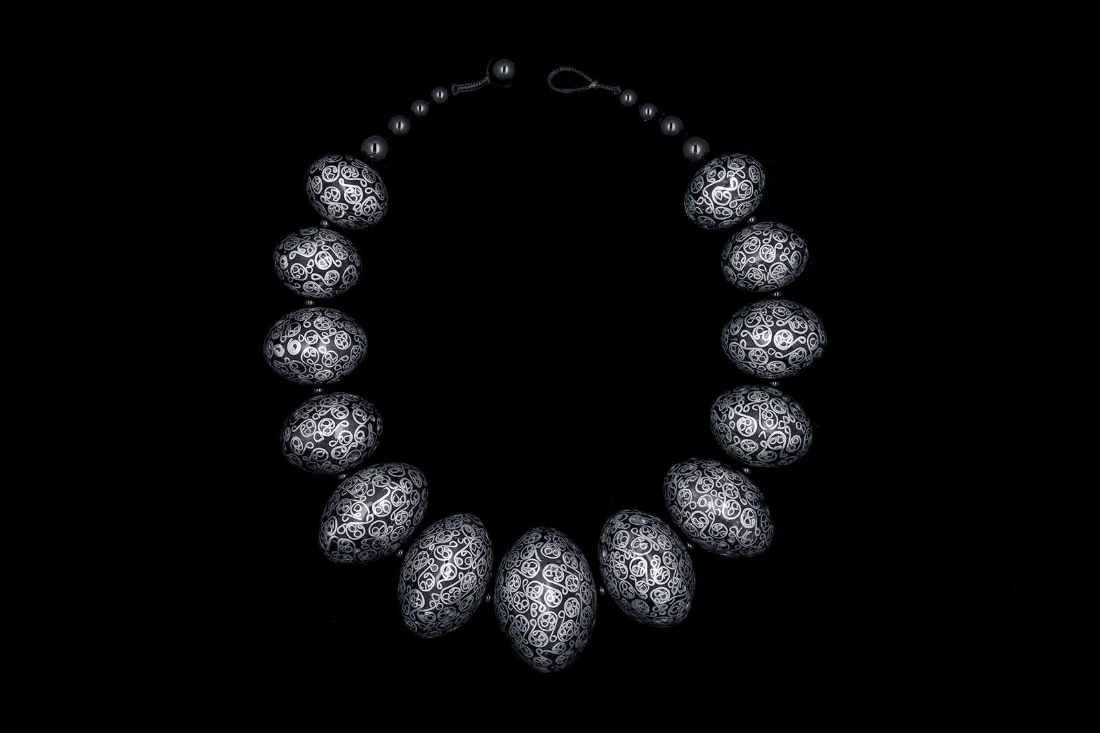 A Necklace Of Graduated Black Metal Rondelle Shaped Hollow Beads Inlaid With Curled Patterns Of Silver Wire Bands.