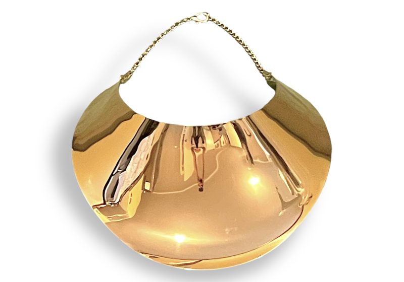 A Large Golden Metal, Polished Surface, Curved And Tapered Band Necklace, Suspended From Two Golden Metal Chains.