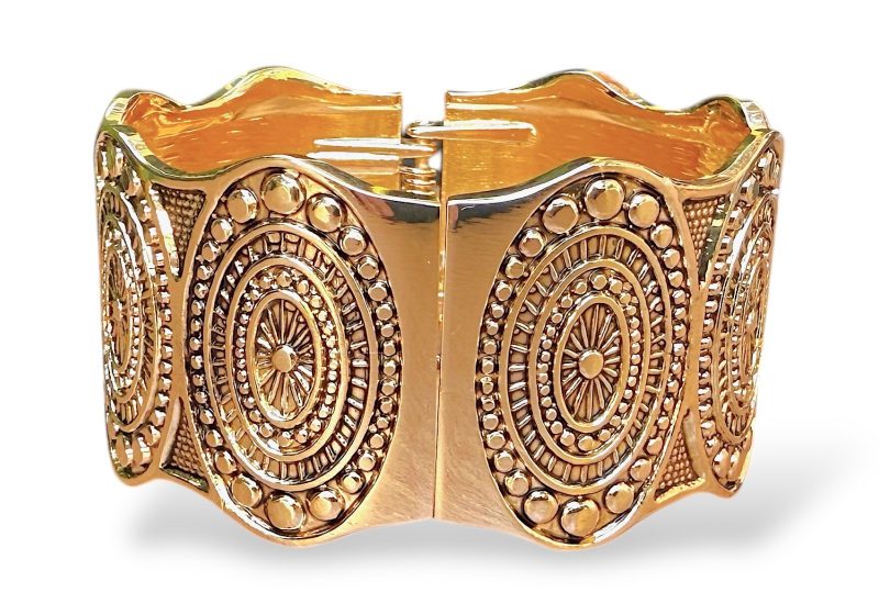 A Golden Metal Hinged Open Bangle Decorated With Eight Engraved Patterned Oval Panels.