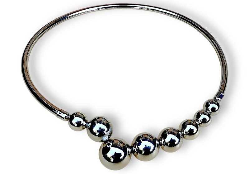 A Silvered Metal Curved Open Band Necklace With Silvered Metal Round Hollow Beads At Each End Of The Band.