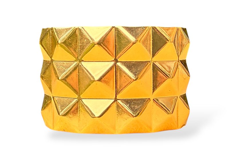 A Golden Metal Open Cuff With Three Bands Of Ten Square Pyramid Shaped Panels.