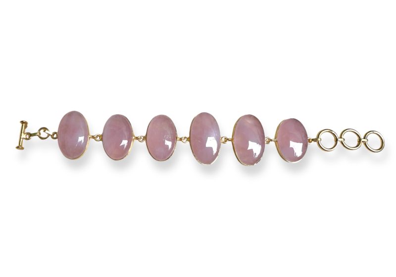 A Gold Plated Bracelet With Six Linked Rose Quartz Domed Oval Cabochons Set In Gold Plated Frames.