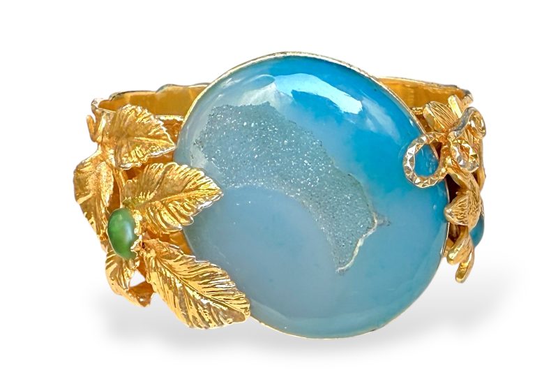 A Golden Metal Floral Patterned Open Cuff With A Large Domed Oval Blue Dyed Agate Druzy Crystal, And Green Glass Cabochons.