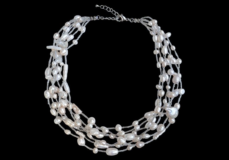 A Seven Strand Necklace Of White Freshwater Pearls And Small Clear Glass Tubular Beads.