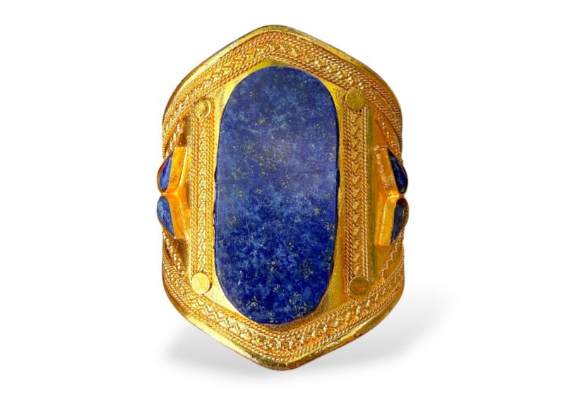 An Afghan Gold Plated Patterned Open Cuff With A Lapis Lazuli Oval Panel At The Centre, And Six Small Lapis Lazuli Inlays