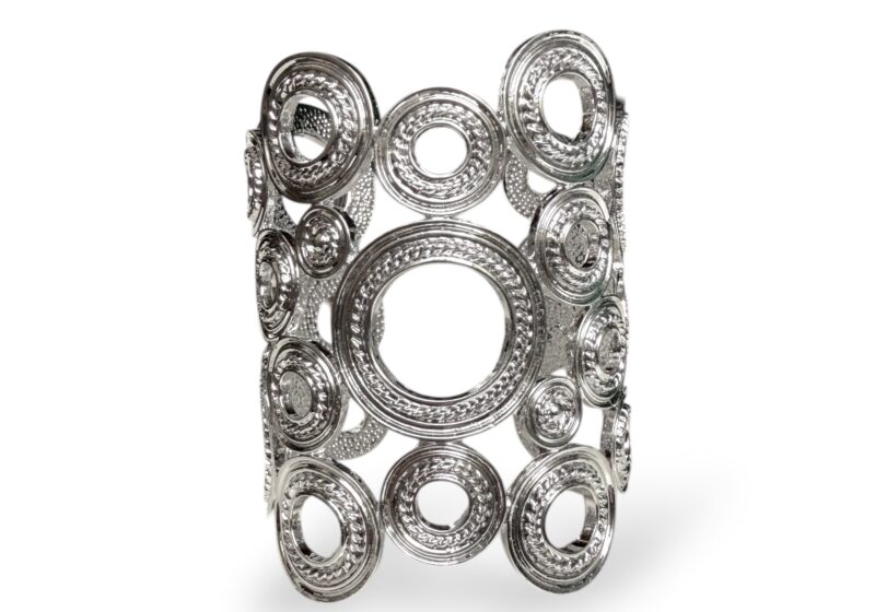 A Long Silvered Metal Open Cuff With A Band Of Mixed Sized Patterned Band Rings.