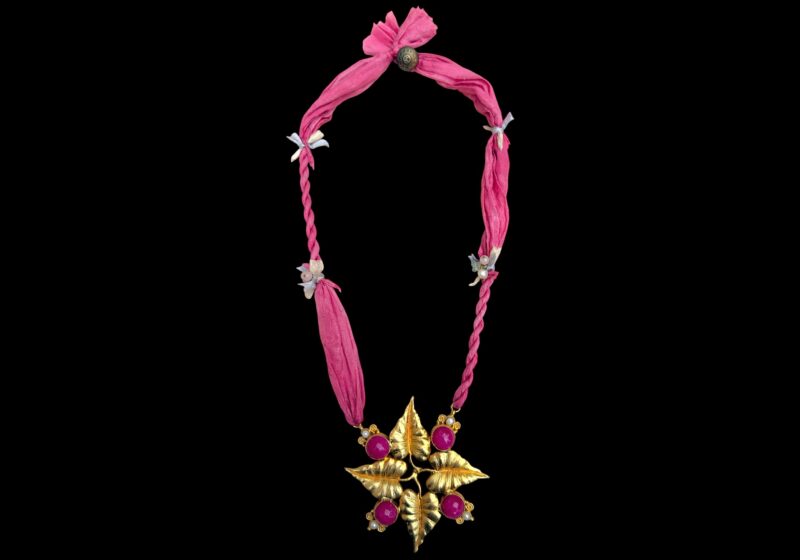 A long Necklace Of Two Pink Silk Strands, With A Gold Plated Four Leaves Pendant, Inlaid With Pink Dyed Domed Circular Facetted Agates, And Small Round White Freshwater Pearls.
