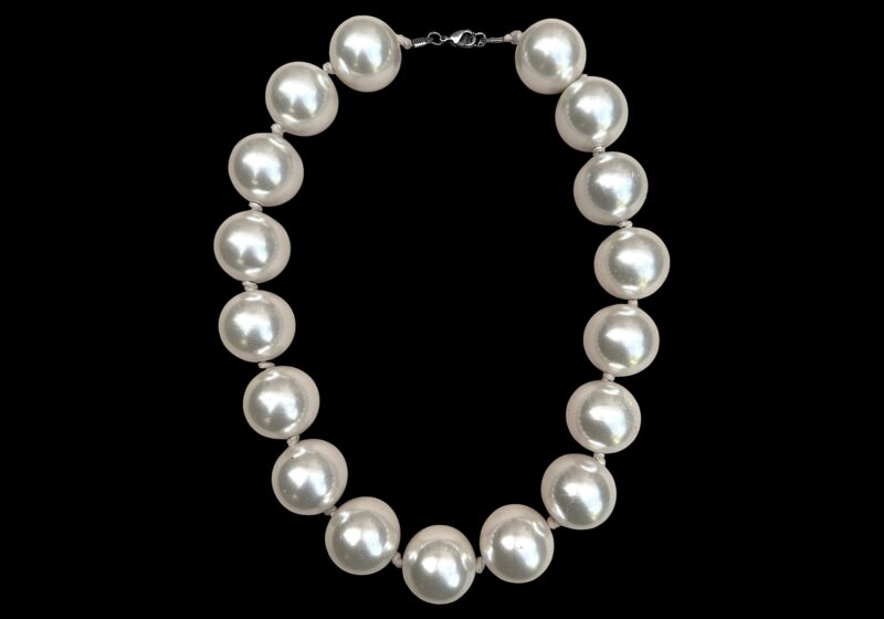 A Long Knotted Necklace Of Seventeen Large White Round Resin 'Faux Pearls'.