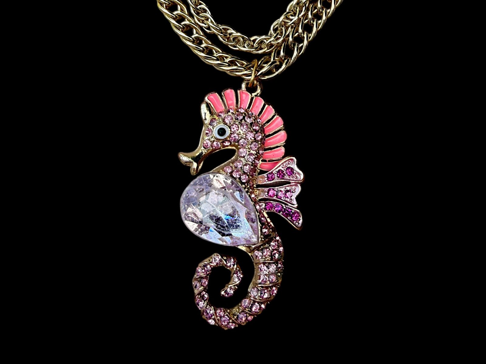 A Golden Metal Two Chains Long Necklace With A Seahorse Pendant Inlaid With Pink And Purple Facetted Glass Beads.