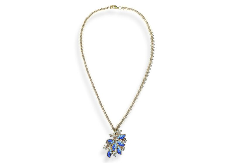 A Golden Metal Long Fishbone Chain Necklace With A Golden Metal Floral Pendant Inlaid With Small Light And Dark Blue Facetted Glass Cabochons.