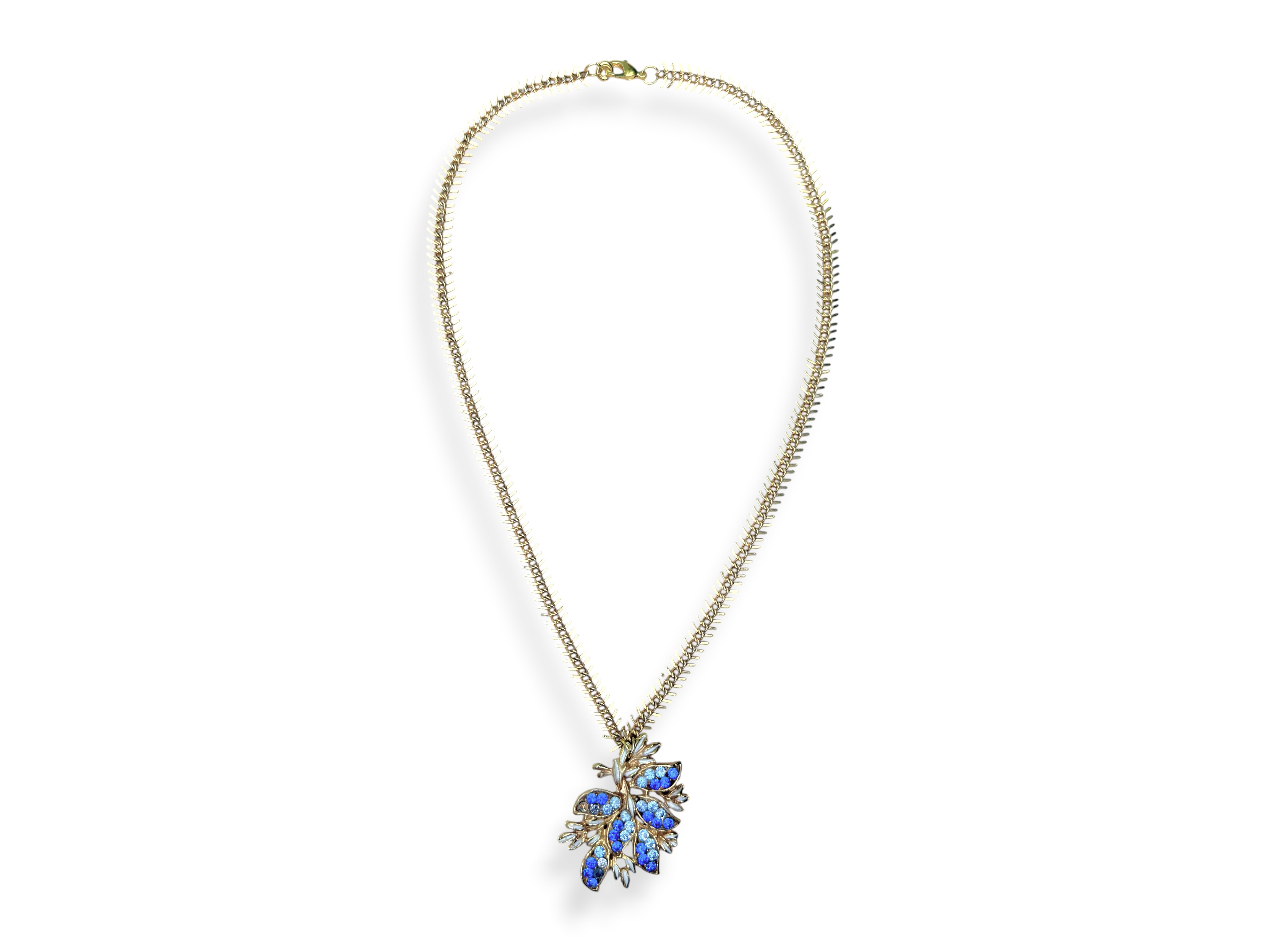 A Golden Metal Long Fishbone Chain Necklace With A Golden Metal Floral Pendant Inlaid With Small Light And Dark Blue Facetted Glass Cabochons.