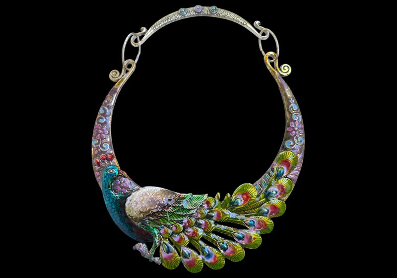 A Silvered Metal Curved Tapered Band Necklace Of A Multicoloured Painted Peacock.