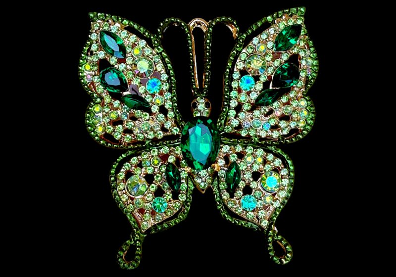 A Golden Metal Butterfly Brooch Inlaid With Facetted Light And Dark Green Glass Facetted Cabochons.