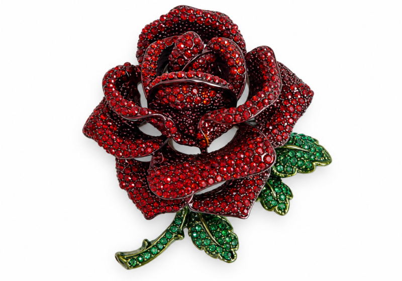 A Silvered metal brooch of a rose inlaid with multicoloured faceted glass cabochons.